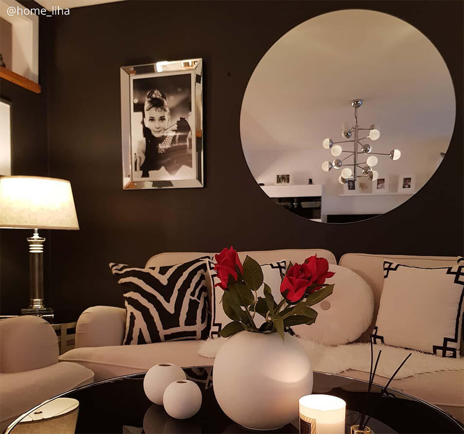 Wohnzimmer mit dunkler Wandfarbe, weißem Sofa und großem, rundem Spiegel