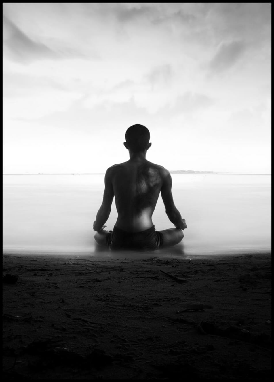 Poster mit Foto, auf dem ein Mann am Strand meditiert